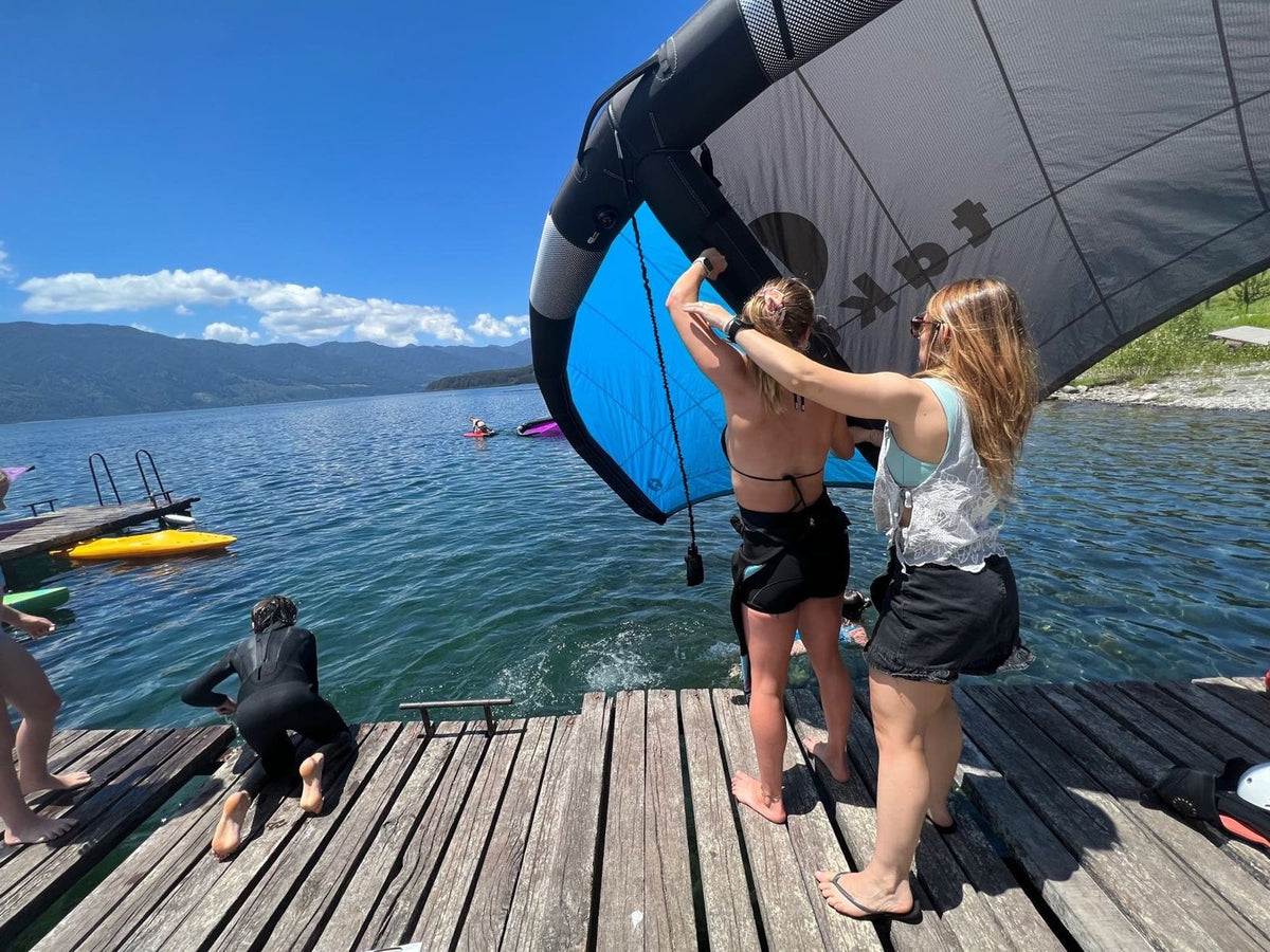 Alumnas armando el ala de wingfoil en un muelle del lago
