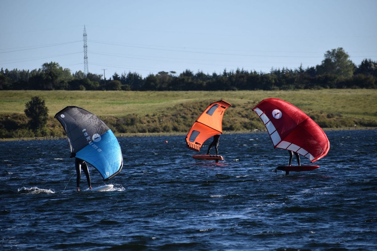 Tres riders haciendo wingfoil en un lago del sur de Chile