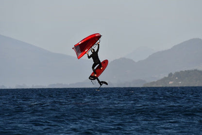 Rider de wingfoil volando sobre el agua con ala roja